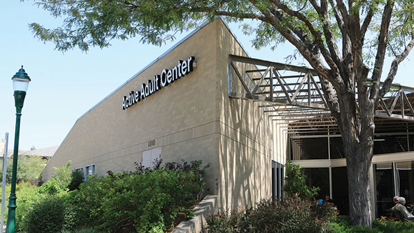 Exterior view of a community building called Active Adult Center surrounded by trees and greenery.