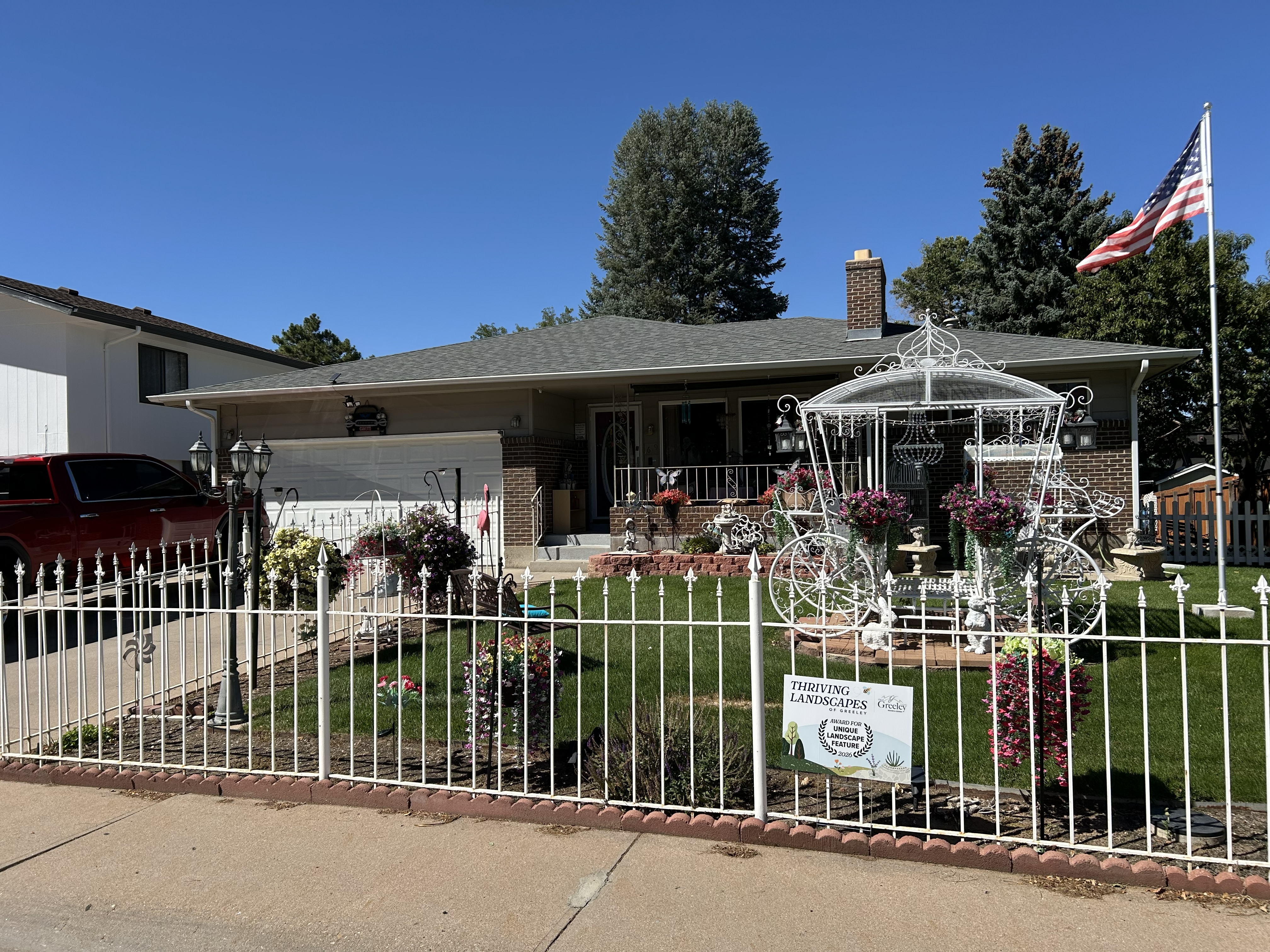 Home with a white fence and flowers in the yard.
