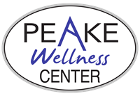 This image displays a logo with the words "Peake Wellness Center" inside an oval-shaped border. The letter "A" in the word Peake is set apart in purple and is stylized to look like a mountain peak.  The word "Wellness" is below the word "Peake" and is also set apart in purple letters that are written in script.  The remaining letters are in an uppercase sans serif font and are black in color.
