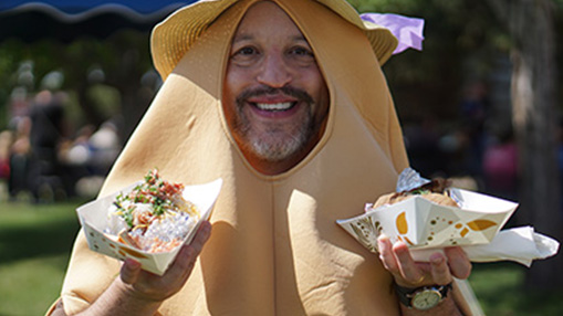 A participant holding dishes showcasing potato-based food at a local outdoor community event.