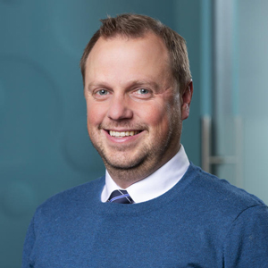 Formal portrait showcasing a person in business attire against an office background.