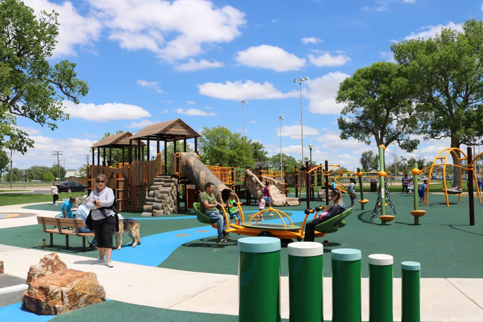 A spacious outdoor playground designed with accessibility features amid green spaces and clear skies.