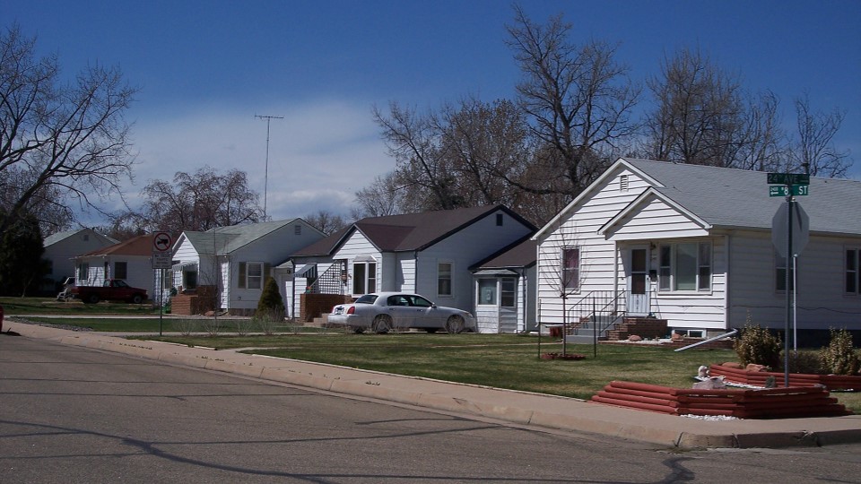 A street lined with houses representing a suburban residential area of Greeley on a sunny day.