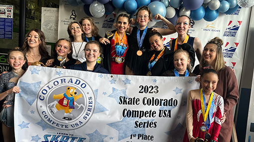 Participants showcasing medals and a banner celebrating their victories at the Skate Colorado Compete USA Series event.