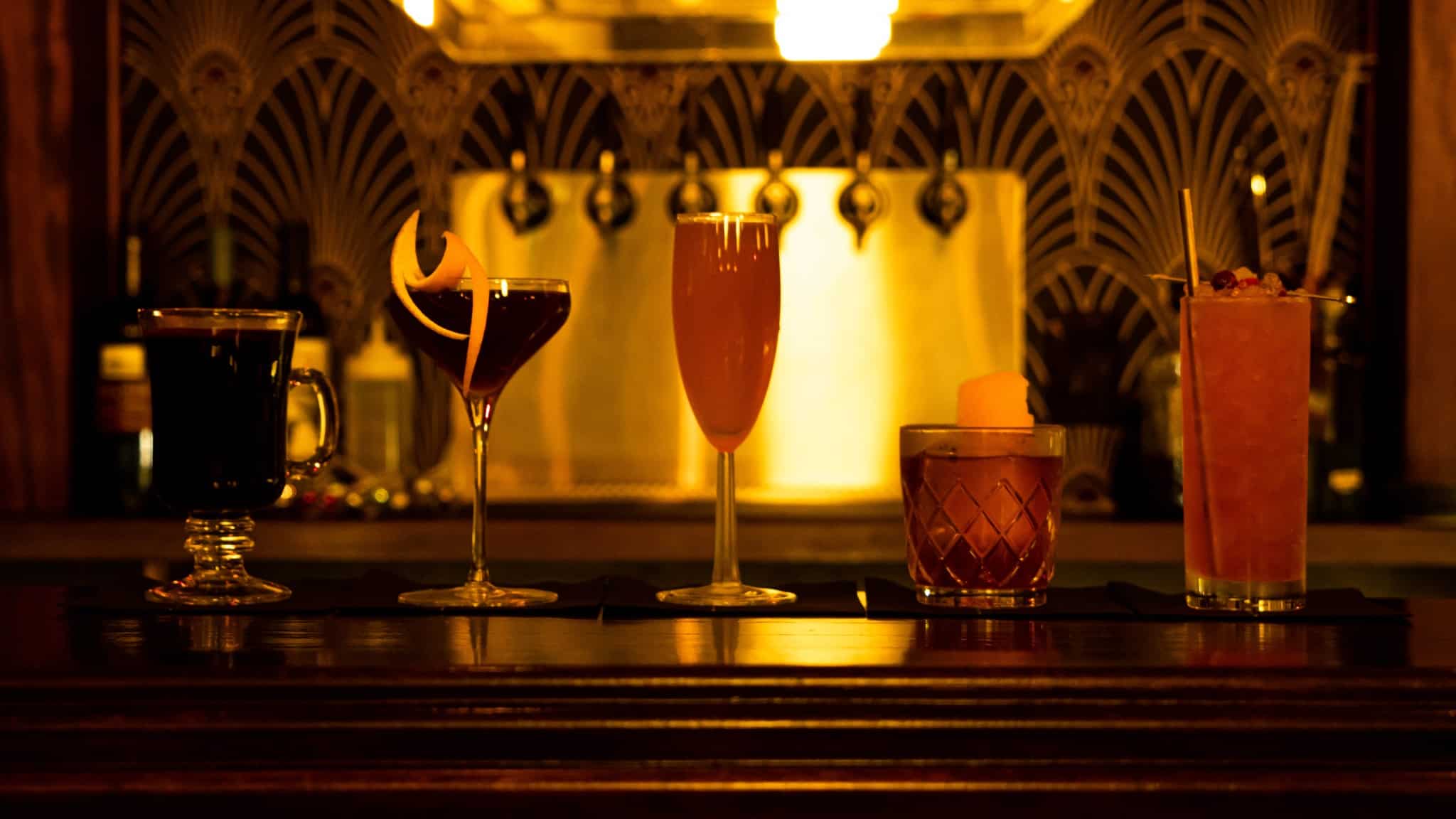 A selection of crafted cocktails elegantly displayed in a warm, vibrant ambience, perfect for nightlife enthusiasts.
