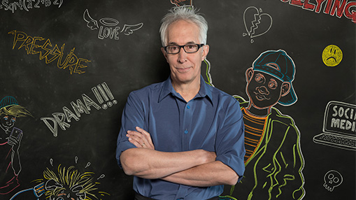 A professional individual poses with a colorful chalkboard highlighting social pressures and challenges of middle school life.
