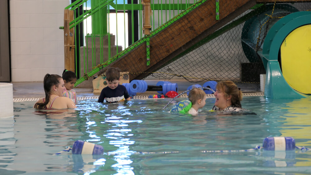 Two instructors work in the pool with swim lesson participants at the Family FunPlex