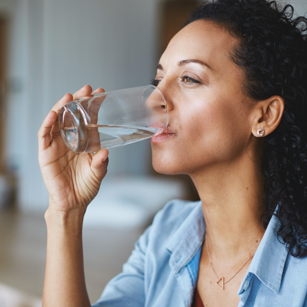 A woman enjoying a refreshing glass of water, symbolizing the importance of daily hydration for well-being.