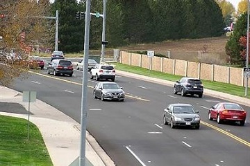 Vehicles moving smoothly on a well-organized roadway surrounded by green spaces and trees.
