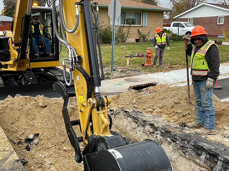 City workers operate machinery and tools to repair water and sewer lines.