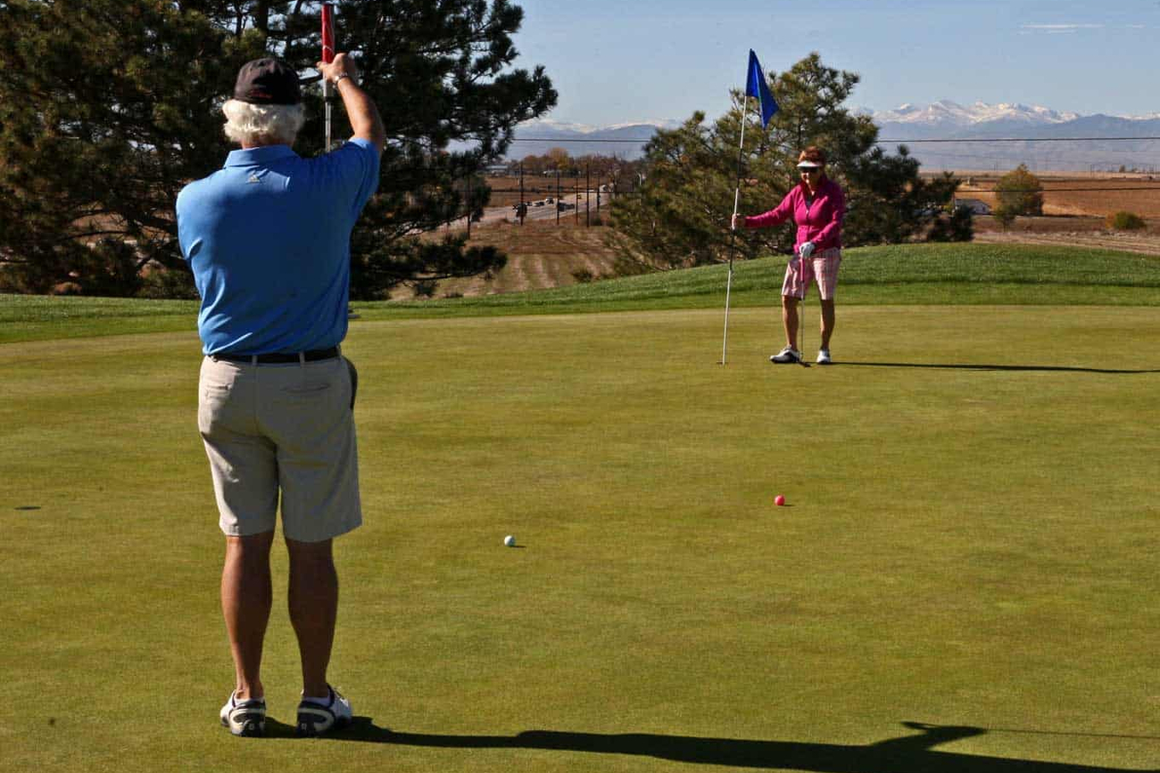 Two golfers engaging in a game on a sunny day at Boomerang Links, surrounded by scenic views of trees and distant mountains.