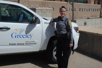 A Greeley Police Department technician standing beside a marked department vehicle, showcasing their role in public safety.
