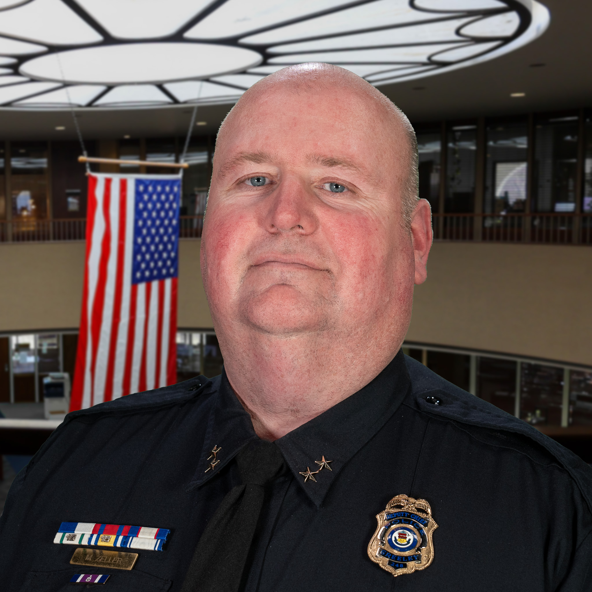 A professional image of a police chief in uniform with an American flag in the background, representing authority and service.