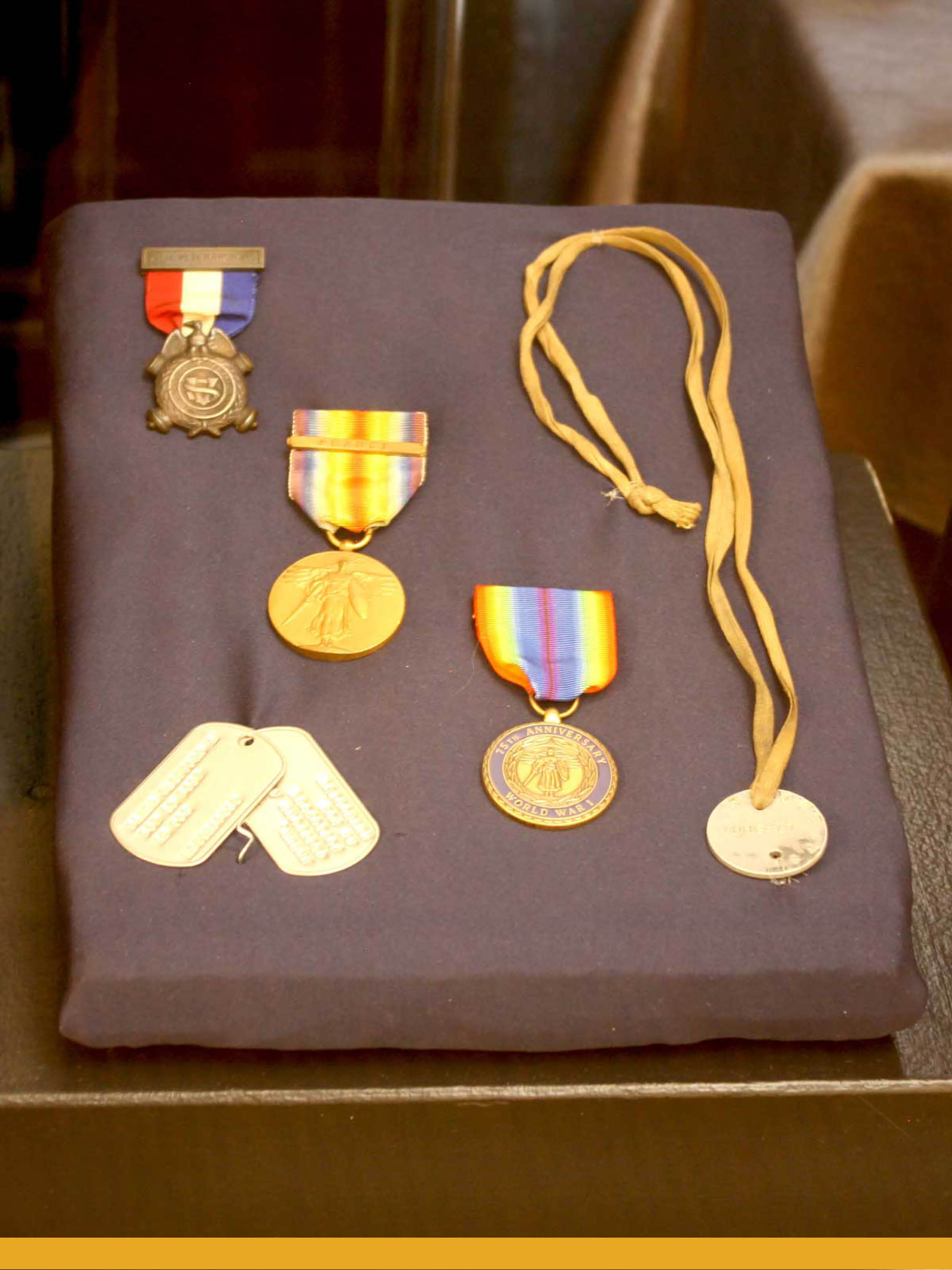 Medals and ID tags on a blue display. Three medals have ribbons and the ID tag has a lanyard.