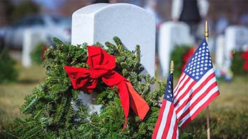 A solemn tribute featuring wreaths and American flags placed at gravesites to honor veterans.
