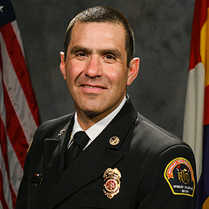 Portrait of a uniformed firefighter with badges, emphasizing professionalism and service.