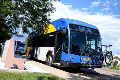 A Greeley bus parked nearby a bench under a sunny sky, offering efficient transportation for residents.