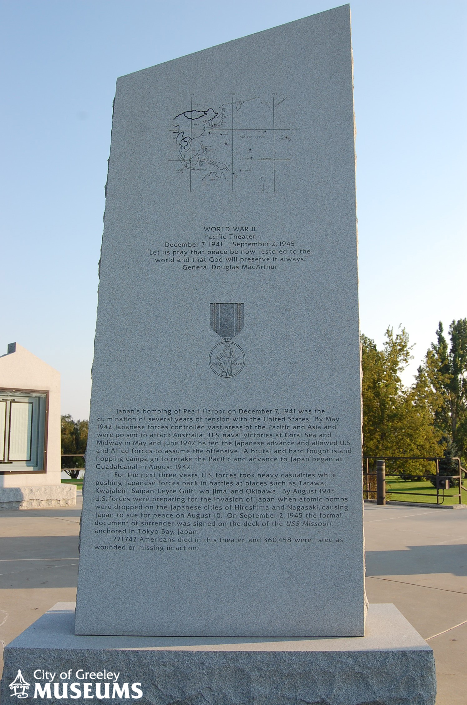 A large stone pillar with writing and a map inscribed on it describing World War II
