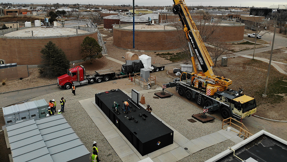 A crane lifts a massive generator off a flatbed truck