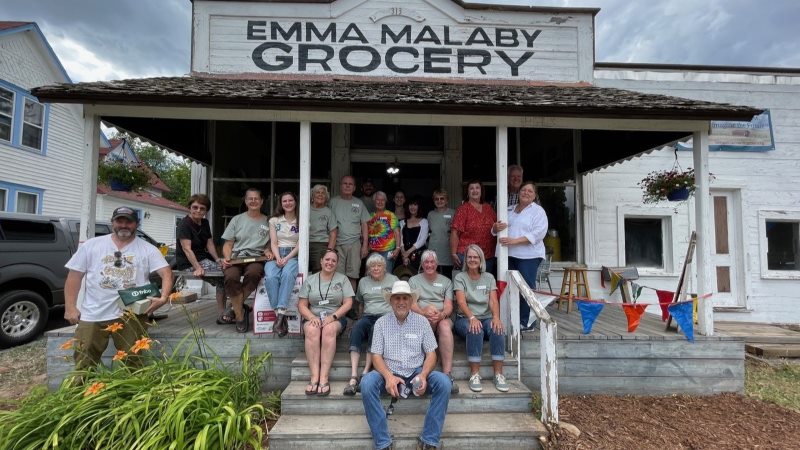 A group of people gathers on the porch of the historic Emma Malaby Grocery in Fort Collins.
