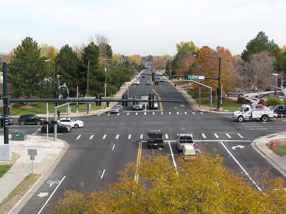 An aerial view of a busy traffic intersection surrounded by trees and infrastructure.