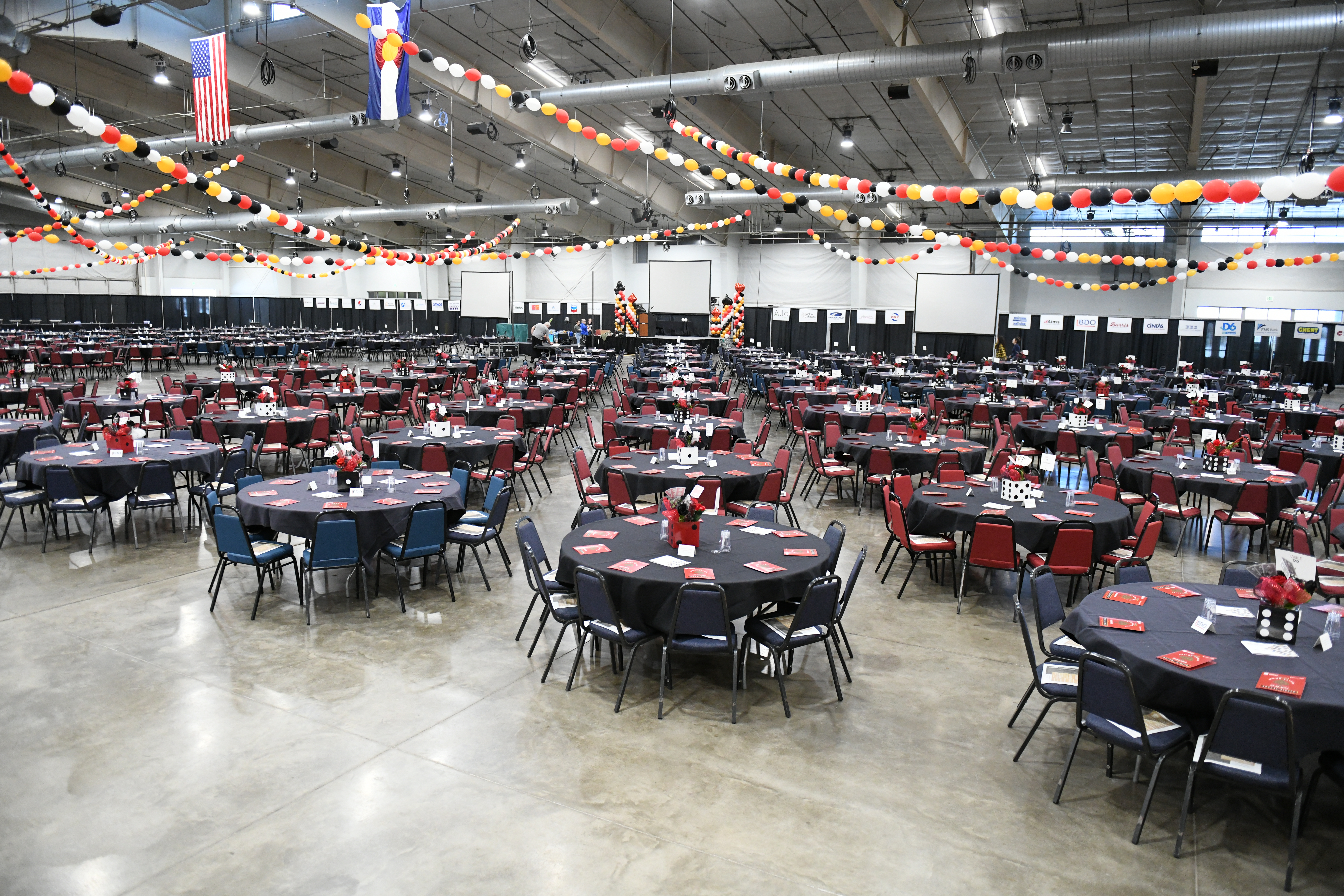 Round, covered tables, place settings, and chairs set up for a formal dining experience at the Banquet Event Center