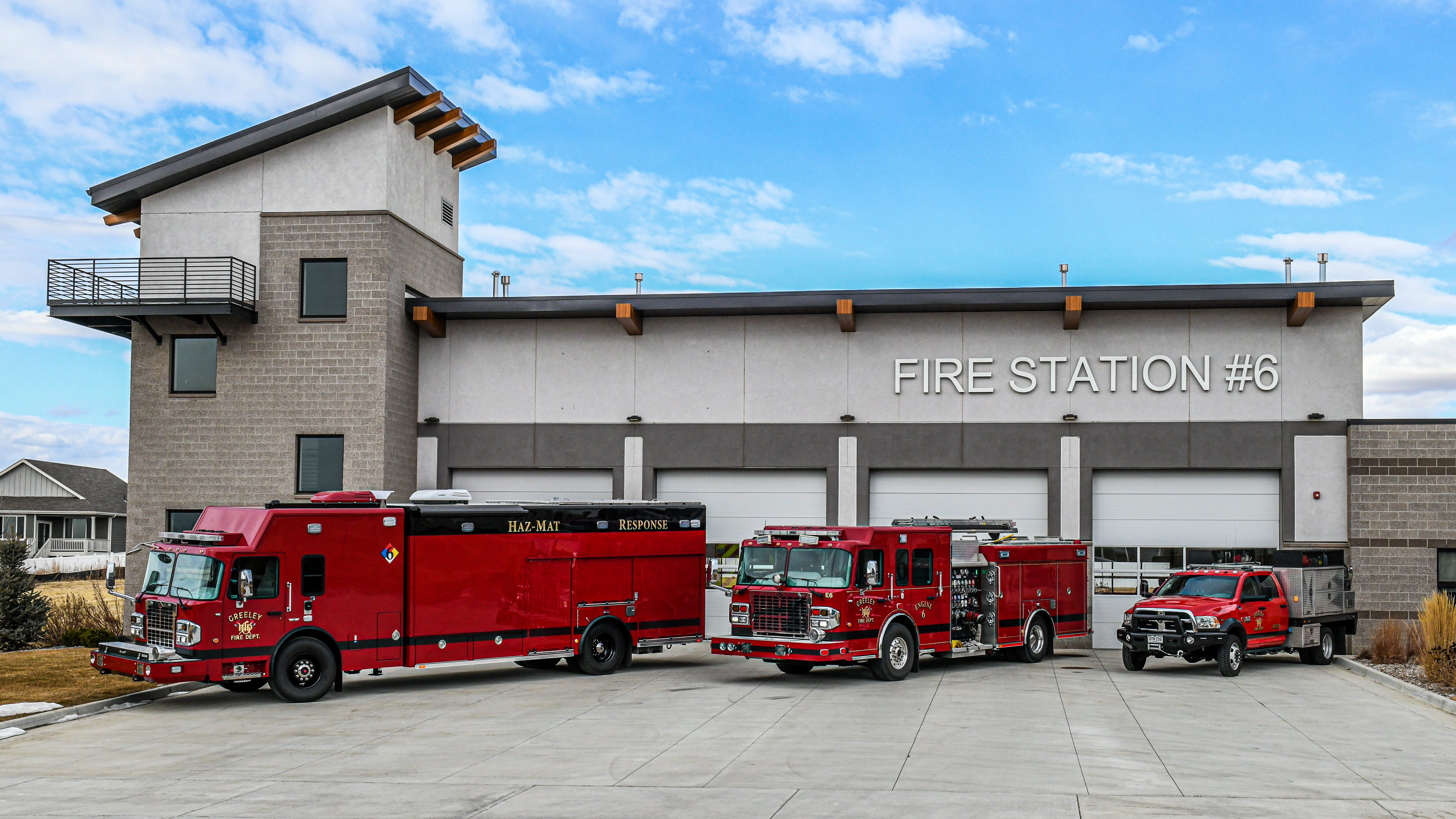 Three firetrucks staged outside of Greeley Fire Station 6 on the front driveway.