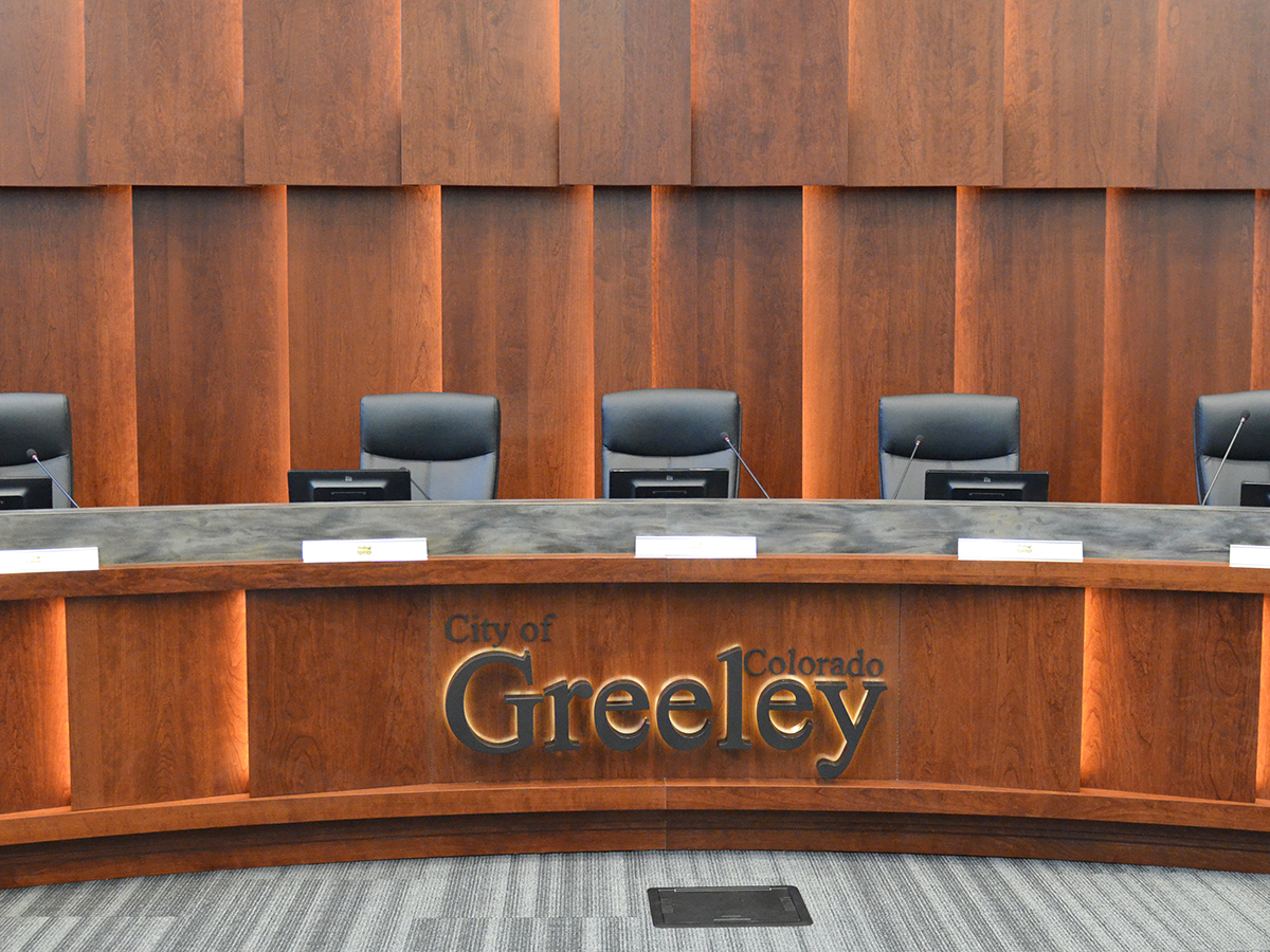 Empty city council chamber seats and the City of Greeley, CO signage