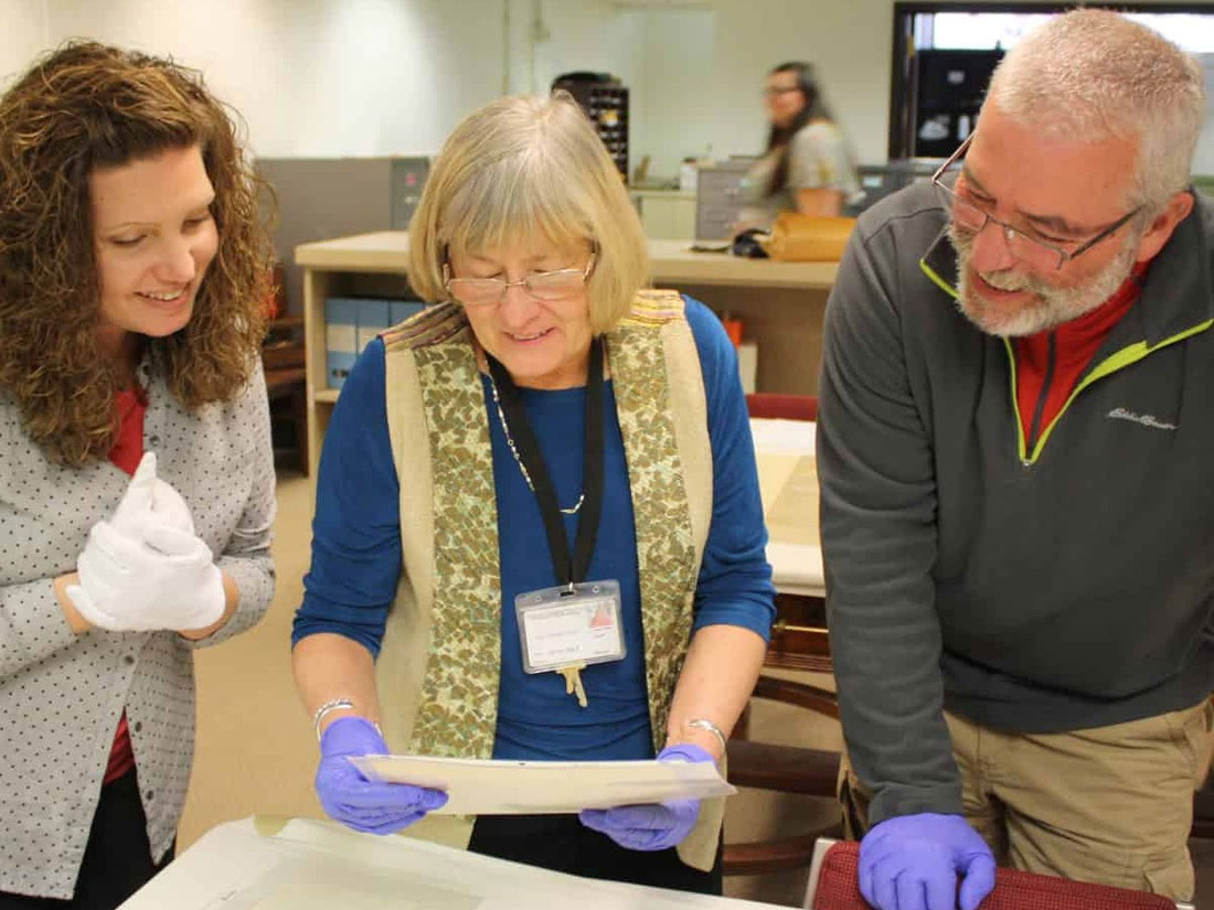 Staff members review historical documents during a collaborative session in a museum workspace.