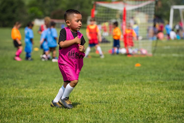 A child participating in a youth soccer practice organized by Greeley Recreation, with vibrant jerseys and a lively background.