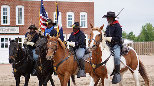 A group of cavalry riders in historical outfits commemorating a significant centennial event.