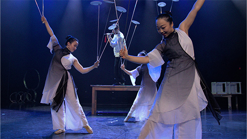 A vibrant performance showcasing skilled artists balancing spinning plates on stage under dramatic lighting.
