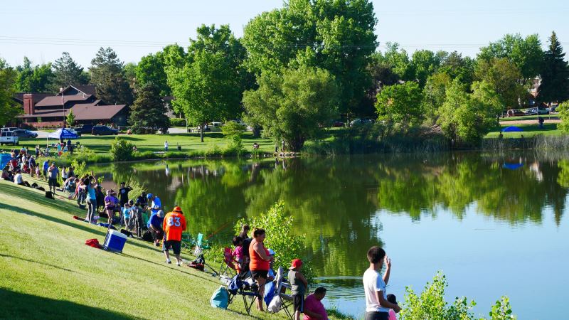 Greeley residents surround the pond at Sanborn Park during the fishing derby, fishing and lounging