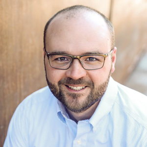 A formal portrait image by a wooden backdrop capturing a professional environment.
