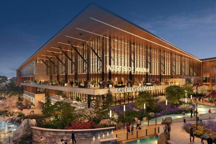 Artist's rendering of the proposed Colorado Eagle's hockey arena to be built in West Greeley.  The building is modern and sleek, with large expanses of glass, metal, and a slanted flat roof.  Large, lit letters on the front of the building read "WEST SIDE ARENA" and "GREELEY, COLORADO".  Raised stone flowerbeds are filled with colorful bushes and shrubbery and a small pond with fountain are off to the left of the building.  A walkway lined with lights and black metal railing allows pedestrians to cross a lazy river that winds around the right side of the building.  The scene is at dusk, with lit street lights lining the walkways.