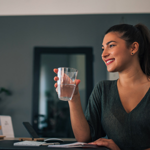 A woman holding a glass of water, promoting sustainability and mindful water usage.