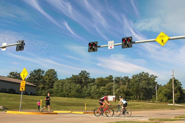 A scene depicting pedestrians and cyclists safely crossing at a Hawk Beacon, highlighting urban mobility and safety measures.