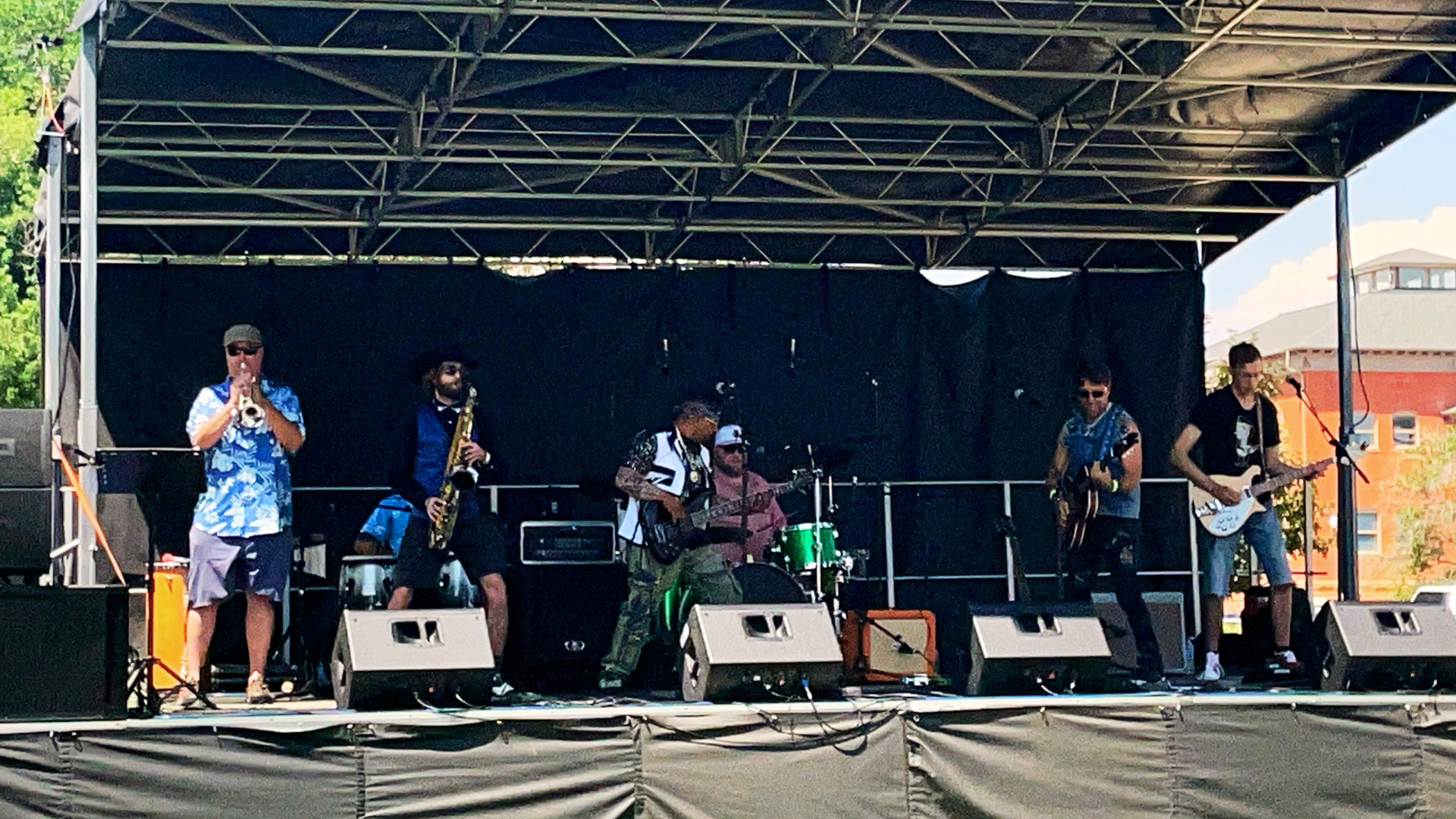 Arts Picnic music stage with band playing lively music on a bright summer day.