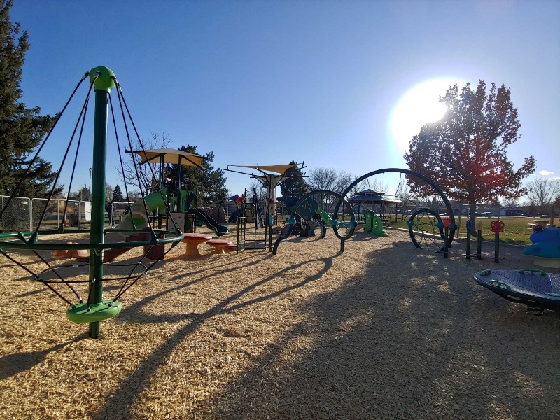 The Broadview Park playground featuring modern play equipment under a clear afternoon sky with sunlight casting long shadows.
