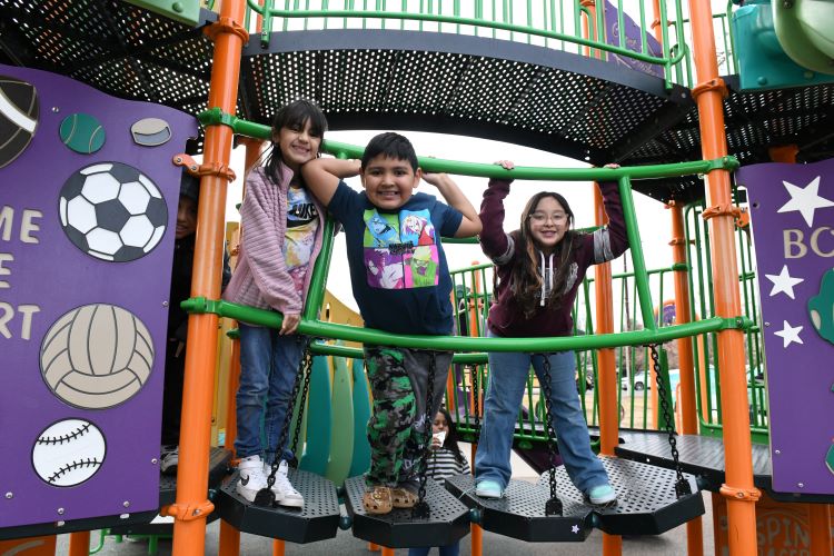 Children engaging in play at the Rodarte Community Center playground, surrounded by colorful sports-themed decorations.