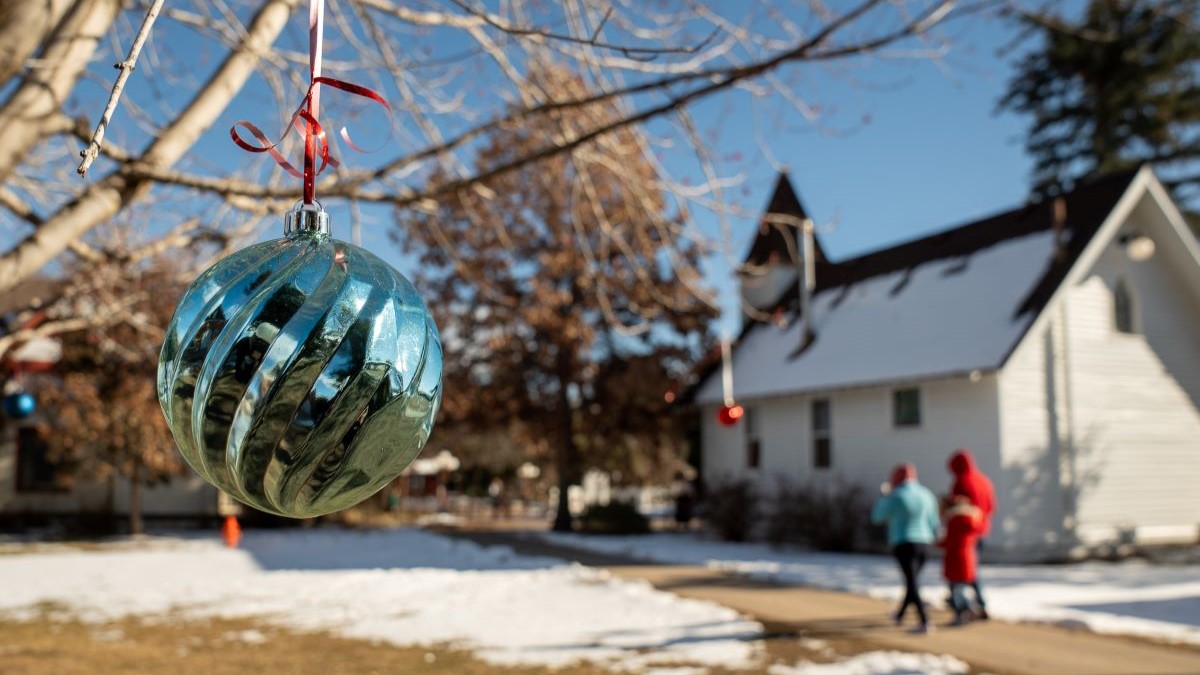 Winter scene with blue Christmas ornament hanging on tree with white historical building in the background
