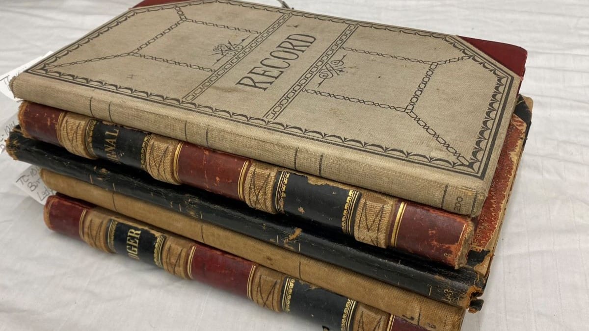 A collection of five vintage ledger books stacked together, with the top book labeled as 'Record'.