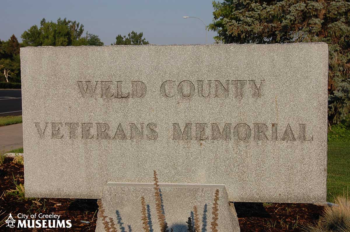 A grey stone marker with the words Weld County Veterans Memorial inscribed on it
