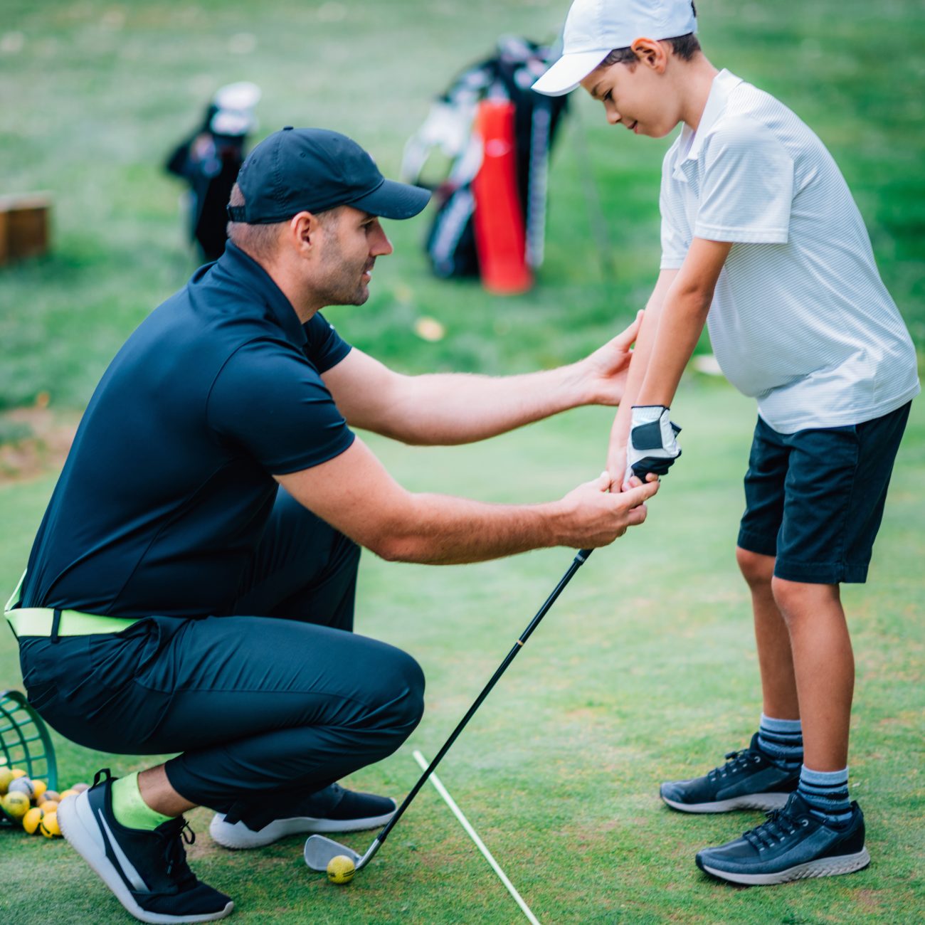 A golf instructor helps a young boy improve his grip on the club during a practice session on the golf course.