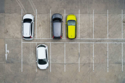 An aerial view of a parking lot showcasing a few cars parked within marked spaces, emphasizing urban organization.