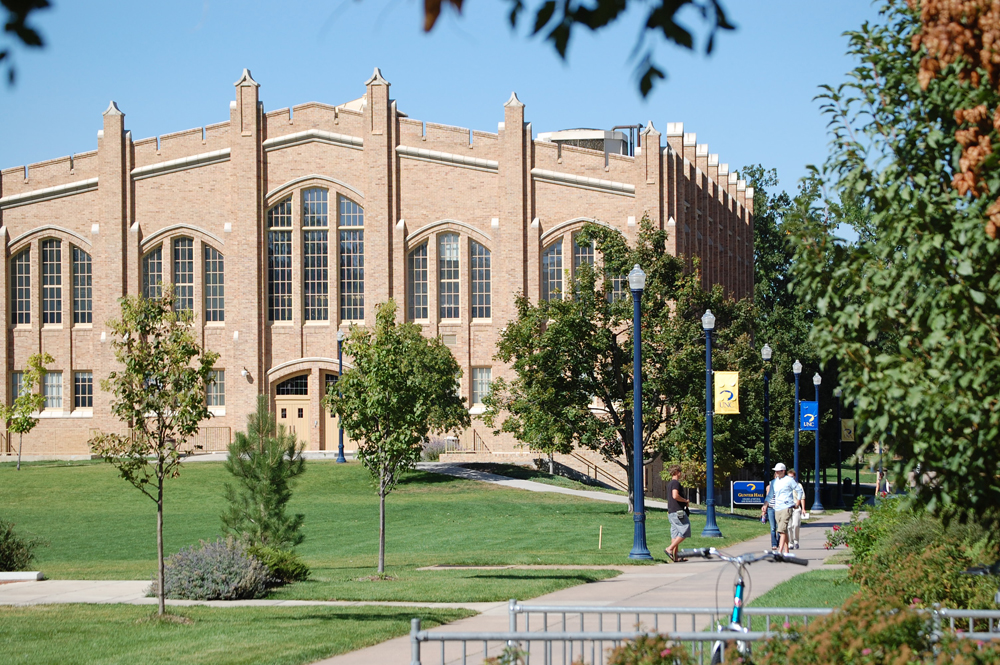 A scenic view of the University of Northern Colorado campus showcasing its historic building and lush greenery on a sunny day.