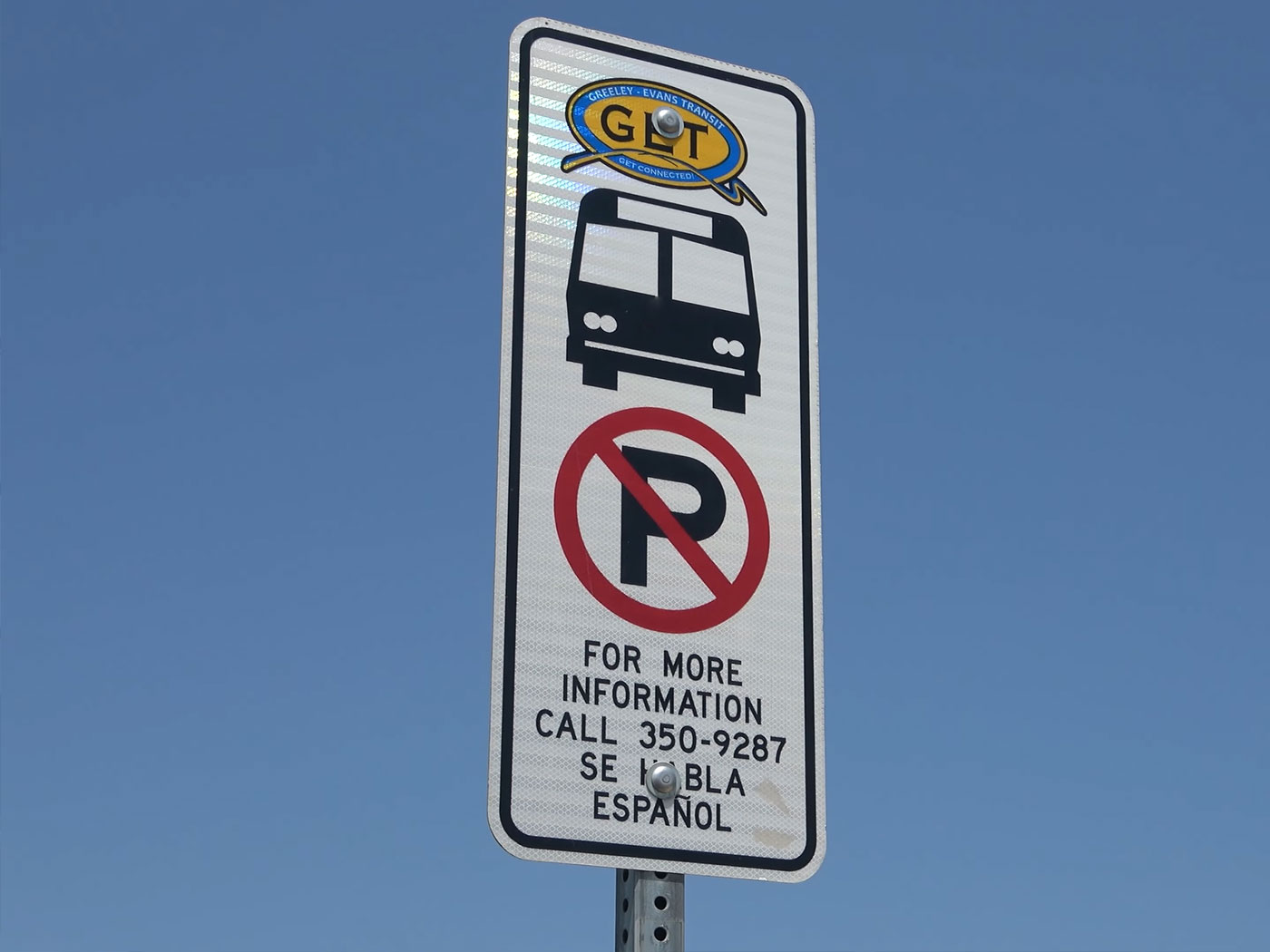 Road sign with the GET logo and symbols for a bus stop and no parking, with text that reads for more information call 350-9287 se habla espanol