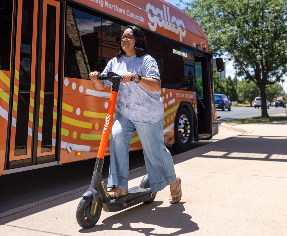 young woman riding a scooter next to a gallop city bus