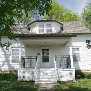 A charming historic farmhouse featuring classic architecture surrounded by lush greenery.