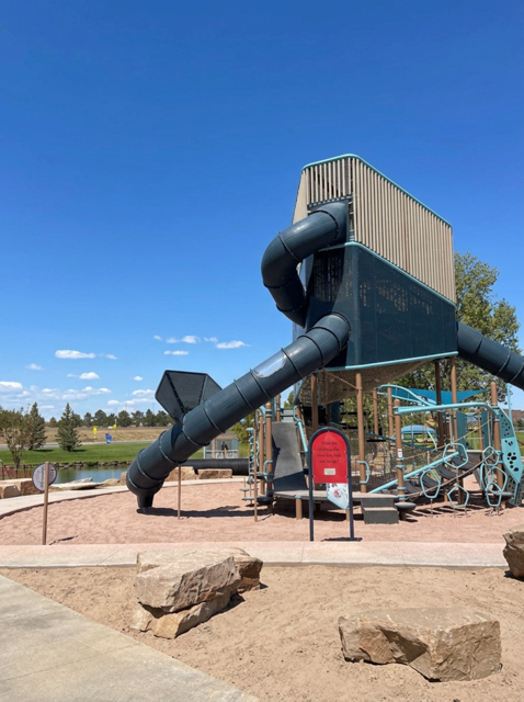A multi-story playground feature with a slide stands prominently above a play space